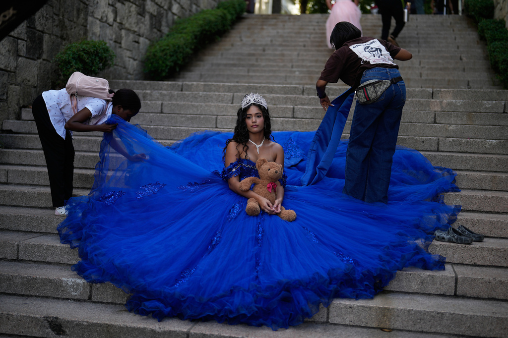 Photo assistants fan out the skirt of quinceañera Franchesca Ovalle's gown during a portrait session in the historic center of Santo Domingo, Dominican Republic, Thursday, July 23, 2026. (AP Photo/Fernando Vergara)