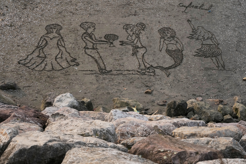 Images are drawn into the sand at the beach of the southern coast of the Caspian Sea outside the port city of Bandar Anzali, Iran, Tuesday, Dec. 23, 2025. (AP Photo/Vahid Salemi)