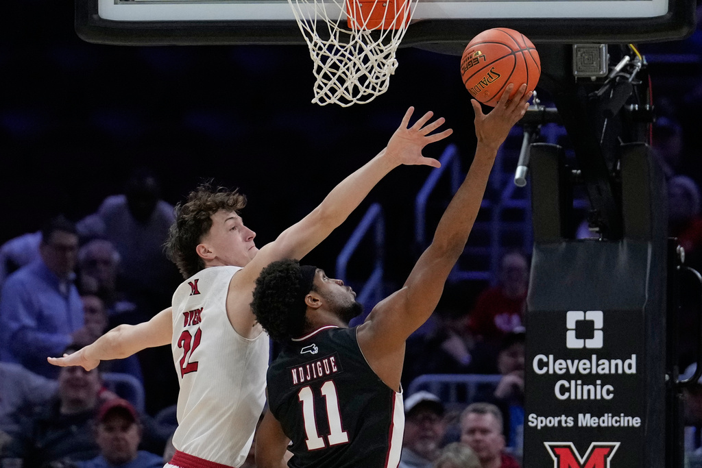 Massachusetts' Jayden Ndjigue (11) shoots as Miami (Ohio) forward Brant Byers (22) defends in the first half of an NCAA college basketball game in the quarterfinals of the Mid-American Conference tournament, Thursday, March 12, 2026, in Cleveland. (AP Photo/Sue Ogrocki)