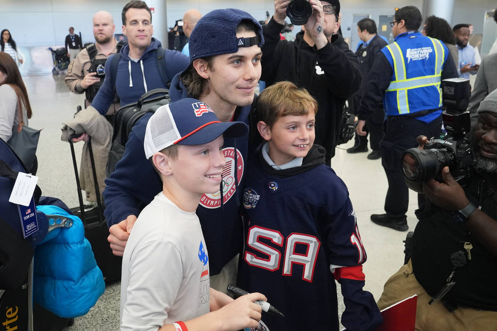 United Stated hockey player Jack Hughes poses with fans after arriving at Miami International Airport after the team won the gold medal at the Milan Cortina Olympics, Monday, Feb. 23, 2026, in Miami. (AP Photo/Marta Lavandier)