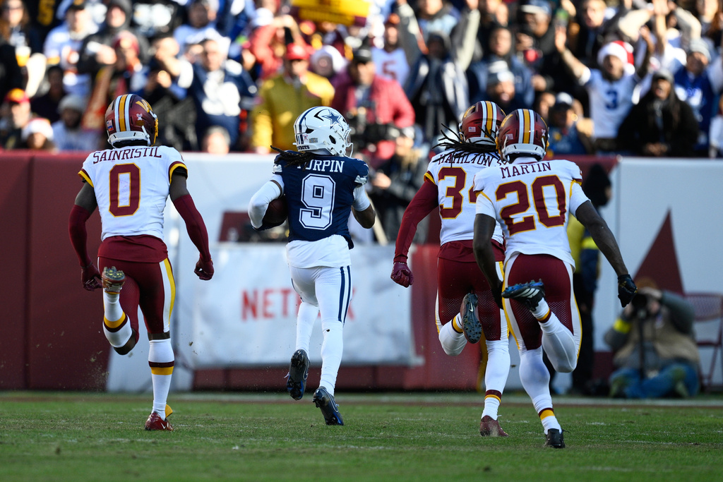 Dallas Cowboys wide receiver Kavontae Turpin (9) heads for the end zone to score on a touchdown pass as Washington Commanders cornerback Mike Sainristil (0), cornerback Antonio Hamilton Sr., and safety Quan Martin (20) give chase during the first half an NFL football game Thursday, Dec. 25, 2025, in Landover, Md. (AP Photo/Nick Wass)