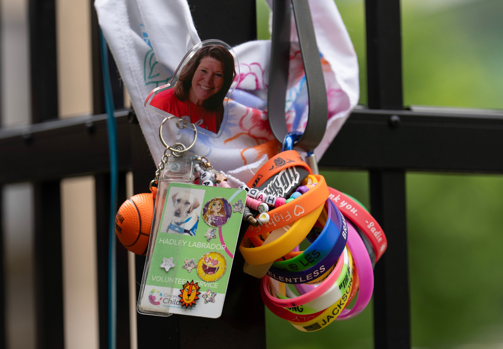 An image of Schellie Scott, a child life assistant and former teacher, and the ID badge of her facility dog Hadley, hang with a leash and bandanna on a fence in the facility dog play area at Cincinnati Children's Hospital Medical Center in Cincinnati, Monday, May 4, 2026. (AP Photo/Carolyn Kaster)