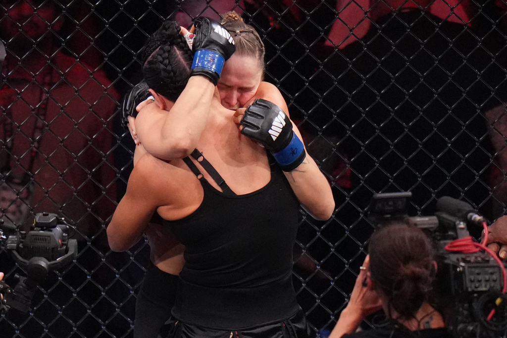 Ronda Rousey, of the United States, behind, hugs Gina Carano, of the United States, after defeating her in their featherweight mixed martial arts fight Saturday, May 16, 2026, in Inglewood, Calif. (AP Photo/Jae C. Hong )