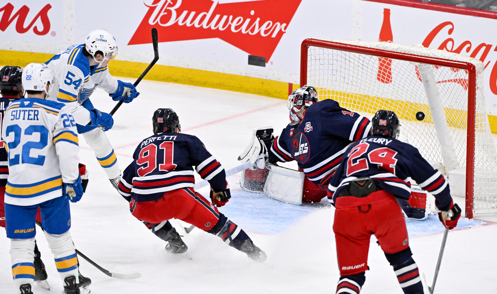 St. Louis Blues' Dalibor Dvorsky (54) scores on Winnipeg Jets goaltender Eric Comrie (1) during the third period of an NHL hockey in Winnipeg, Manitoba, Sunday March 15, 2026. (Fred Greenslade/The Canadian Press via AP)