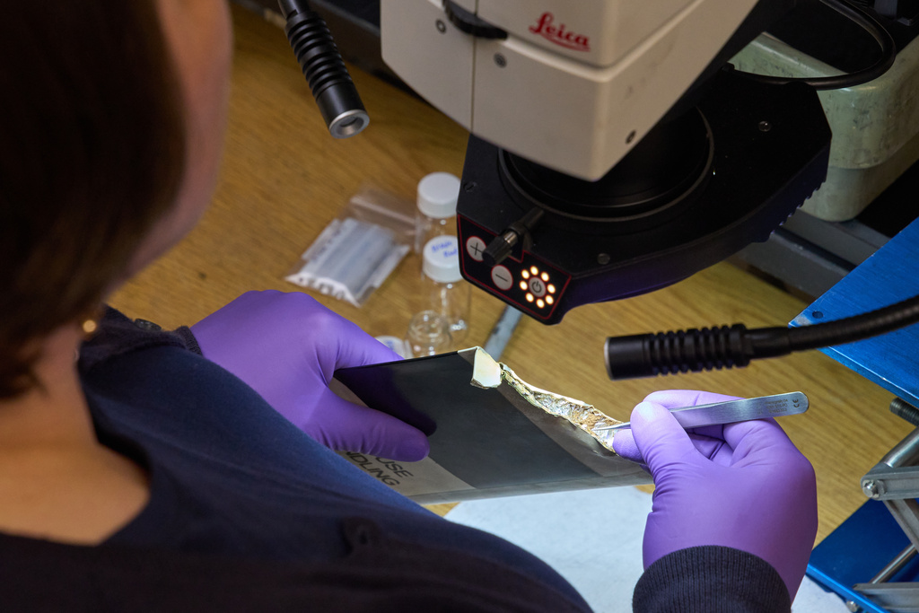 Materials Engineer Adrienne Lamm, uses an optical microscope to examine debris from inside the tail rotor blade of a helicopter, inside the Materials Laboratory of the National Transportation Safety Board (NTSB), Tuesday, Jan. 20, 2026, in Washington. (AP Photo/Jacquelyn Martin)