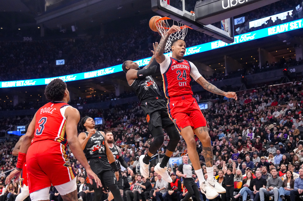 Toronto Raptors' RJ Barrett, second from right, scores against New Orleans Pelicans' Jordan Hawkins (24) during first-half NBA basketball game action in Toronto, Friday March 27 2026. (Chris Young/The Canadian Press via AP)