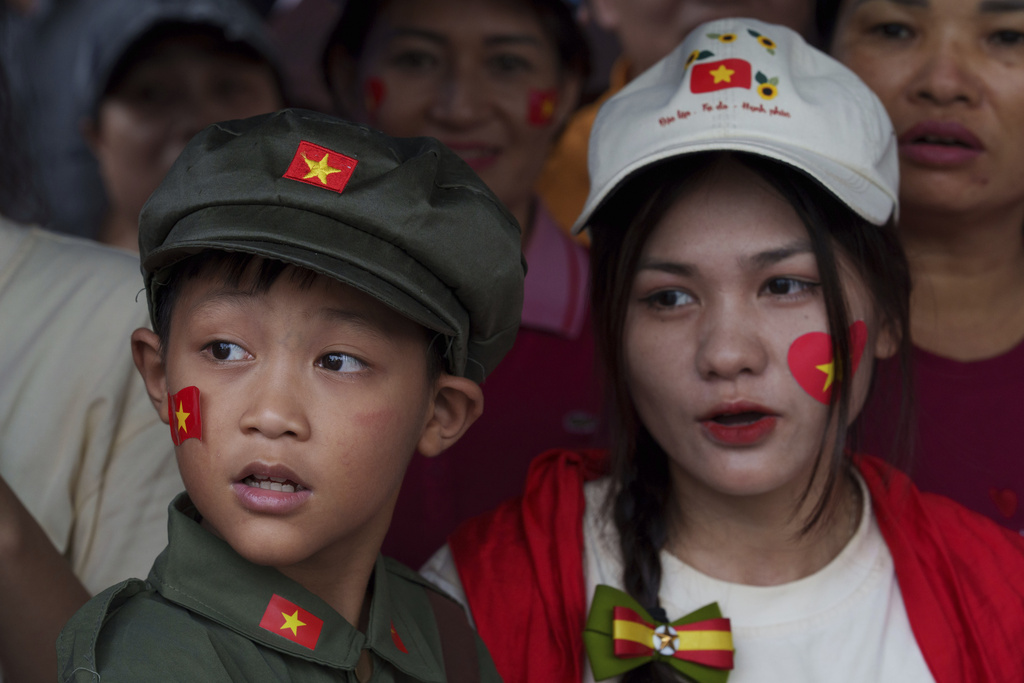 A child wears a traditional Vietnamese military uniform as people wait for a military parade rehearsal for the 80th National Day celebration in Hanoi, Vietnam, Saturday, Aug. 30, 2025. (AP Photo/Vincent Thian)