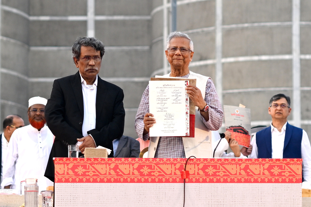 Head of the Bangladesh's interim government and Nobel laureate Dr. Muhammad Yunus, center right, displays a political charter called 'July National Charter' at an event outside Bangladesh's national parliament complex in Dhaka, Bangladesh, Friday, Oct. 17, 2025. (AP Photo/Mahmud Hossain Opu)