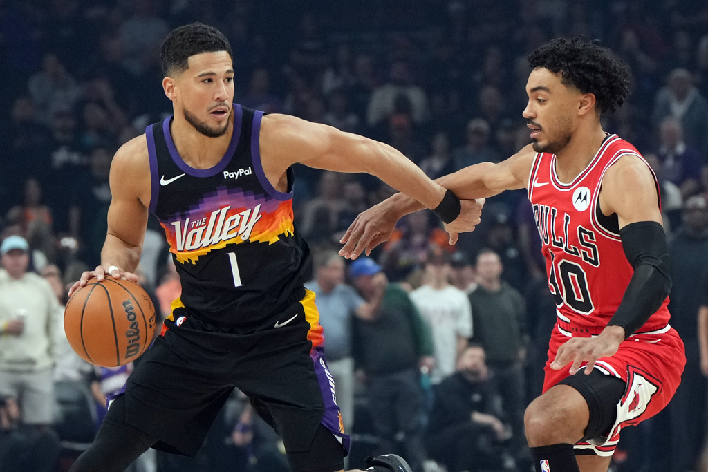 Phoenix Suns guard Devin Booker (1) shields the ball from Chicago Bulls guard Tre Jones during the first half of an NBA basketball game, Thursday, March 5, 2026, in Phoenix. (AP Photo/Rick Scuteri)