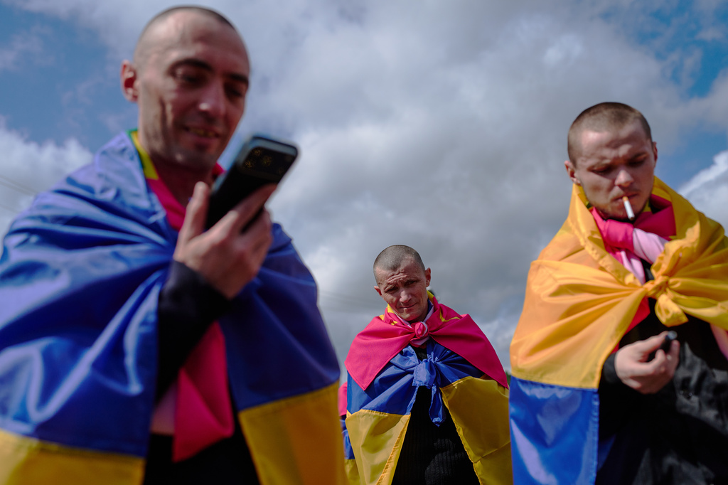Ukrainian soldiers smoke and talk to their relatives after returning from captivity after a Prisoners of War (POWs) exchange between Russia and Ukraine, in Chernyhiv region, Ukraine, Wednesday, Aug. 19, 2026. (AP Photo/Francisco Seco)