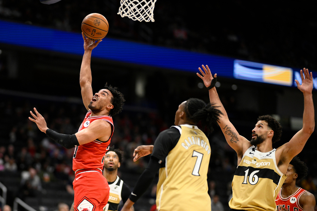 Chicago Bulls guard Tre Jones, left, goes to the basket past Washington Wizards guard Bub Carrington (7) and forward Anthony Gill (16) during the first half of an NBA basketball game, Thursday, April 9, 2026, in Washington. (AP Photo/Nick Wass)