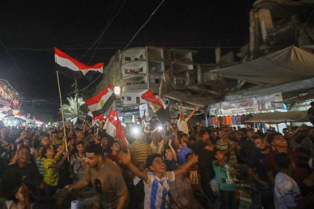 A crowd, some waving Egyptian flags, watches the Egypt-Belgium World Cup match on a giant screen in Nuseirat, central Gaza Strip, Monday, June 15, 2026. (AP Photo/Yousef Al Zanoun)