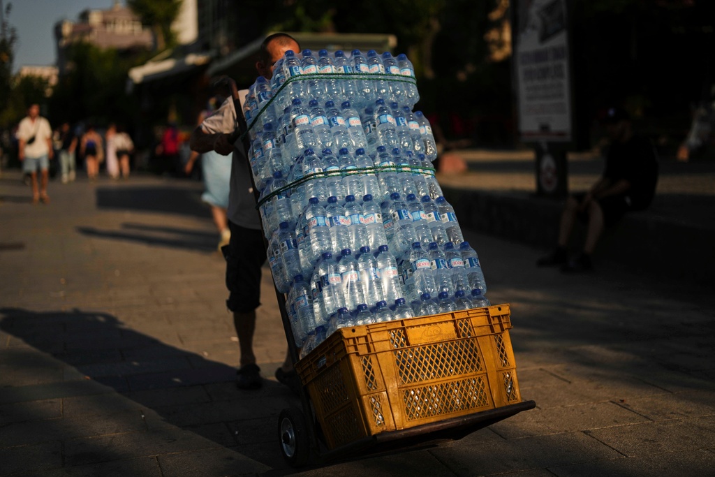 FILE - A man delivers plastic bottles of water to a popular restaurant on a hot summer day, in Istanbul, Turkey, July 24, 2025. (AP Photo/Francisco Seco, File)