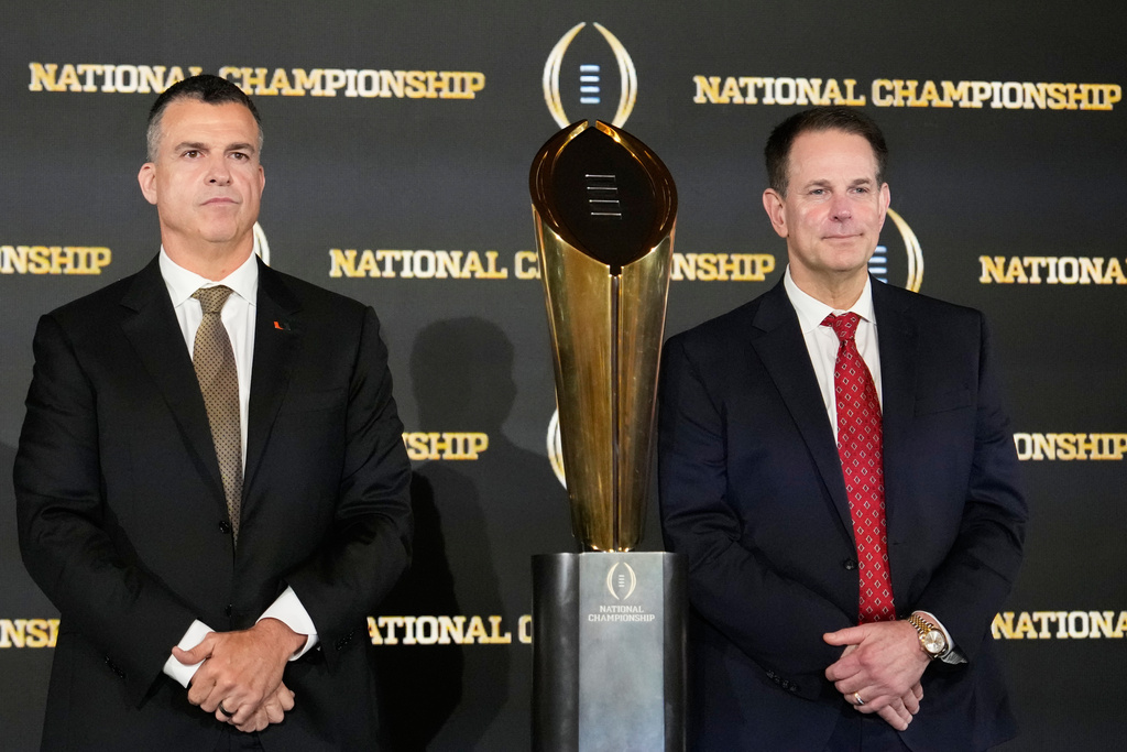Miami head coach Mario Cristobal and Indiana head coach Curt Cignetti pose with the trophy after a news conference ahead of the College Football Playoff national championship game between Miami and Indiana, Sunday, Jan. 18, 2026, in Miami. The game will be played on Monday. (AP Photo/Chris Carlson)