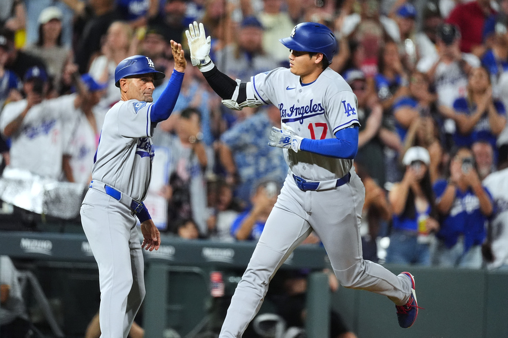 Los Angeles Dodgers third base coach Dino Ebel, left, congratulates Shohei Ohtani (17) who rounds the bases after hitting a two-run home run off Colorado Rockies relief pitcher Juan Mejia in the sixth inning of a baseball game Monday, Aug. 17, 2026, in Denver. (AP Photo/David Zalubowski)