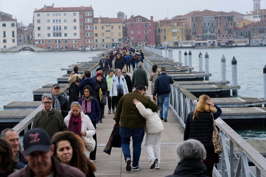 Mourners walk on the 'Votif' Bridge, a 407m temporary floating bridge connecting the city to the cemetery on the island of San Michele, to pay respects to their dead on All Soul's Day, in Venice, Italy, Sunday, Nov. 2, 2025. (AP Photo/Luca Bruno)