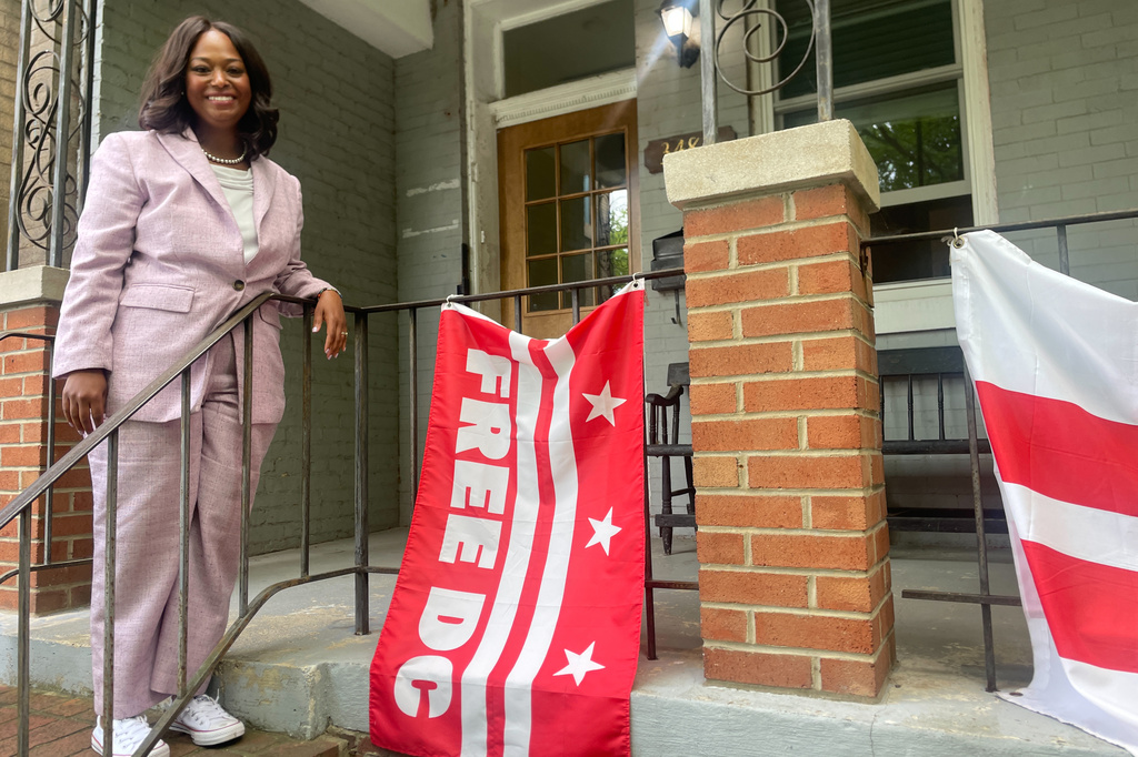 District of Columbia mayoral candidate Janeese Lewis George poses with a Free DC flag while canvassing in a Washington, neighborhood, Monday, June 15, 2026. (AP Photo/Matt Brown)
