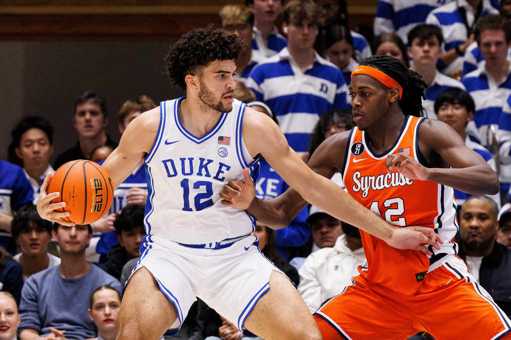 Duke's Cameron Boozer (12) handles the ball as Syracuse's William Kyle III, right, defends during the first half of an NCAA college basketball game in Durham, N.C., Monday, Feb. 16, 2026. (AP Photo/Ben McKeown)