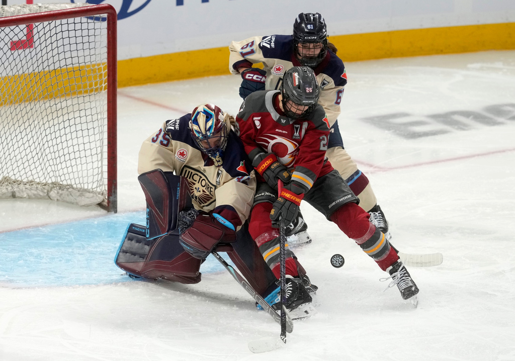Montreal Victoire defense Nicole Gosling (61) looks on as goalie Ann-Renee Desbiens (35) battles Ottawa Charge forward Emily Clark (26) for the puck during the second period of Game 3 in the PWHL Walter Cup finals hockey series in Ottawa, Ontario, Monday May 18, 2026. (Adrian Wyld/The Canadian Press via AP)