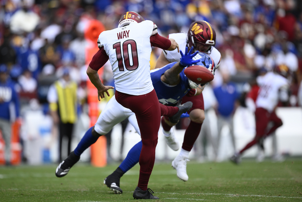 Washington Commanders punter Tress Way (10) gets rid of the ball ahead of New York Giants linebacker Abdul Carter (51) during the second half of an NFL football game, Sunday, Sept. 7, 2025, in Landover, Md. (AP Photo/Nick Wass)