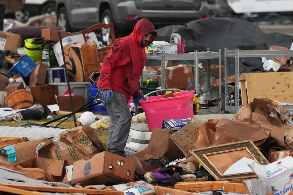A person searches through his belongings amid debris in the aftermath of a powerful storm that ripped through the area a day earlier, in Three Rivers, Mich., Saturday, March 7, 2026. (AP Photo/Nam Y. Huh)