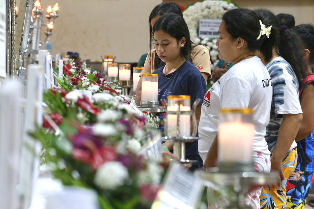 Relatives and friends stand near coffins in Bacayan, Cebu province, Philippines on Friday Nov. 7, 2025 after Typhoon Kalmaegi devastated the province and claimed lives. (AP Photo/Jacqueline Hernandez)
