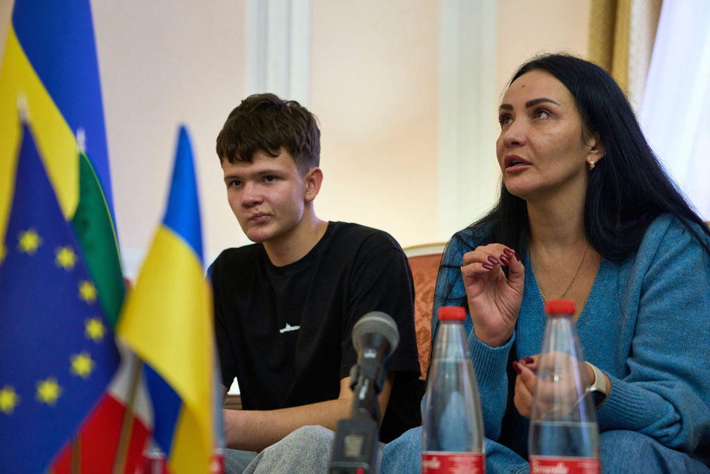 Mark Razvozov, left, listens to his mother Yukiia Dvornychenko, during a press conference on the return of Ukrainian children and civilians taken by Russia during the three-and-a-half-year war, at the Embassy of Ukraine in Italy, in Rome, Wednesday, Nov. 19, 2025. (AP Photo/Domenico Stinellis)