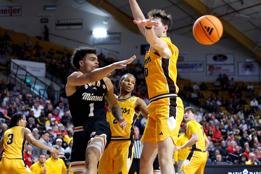 Miami (Ohio) guard Trey Perry (1) dishes off the ball against Western Michigan forward Max Burton during the first half of an NCAA college basketball game, Friday, Feb. 27, 2026, in Kalamazoo, Mich. (AP Photo/Al Goldis)