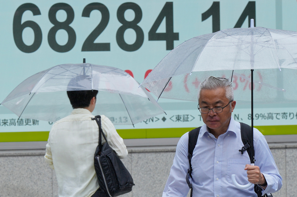 People walk in the rain near electronic stock board showing Japan's Nikkei index at a securities firm Thursday, Aug. 13, 2026, in Tokyo. (AP Photo/Eugene Hoshiko)