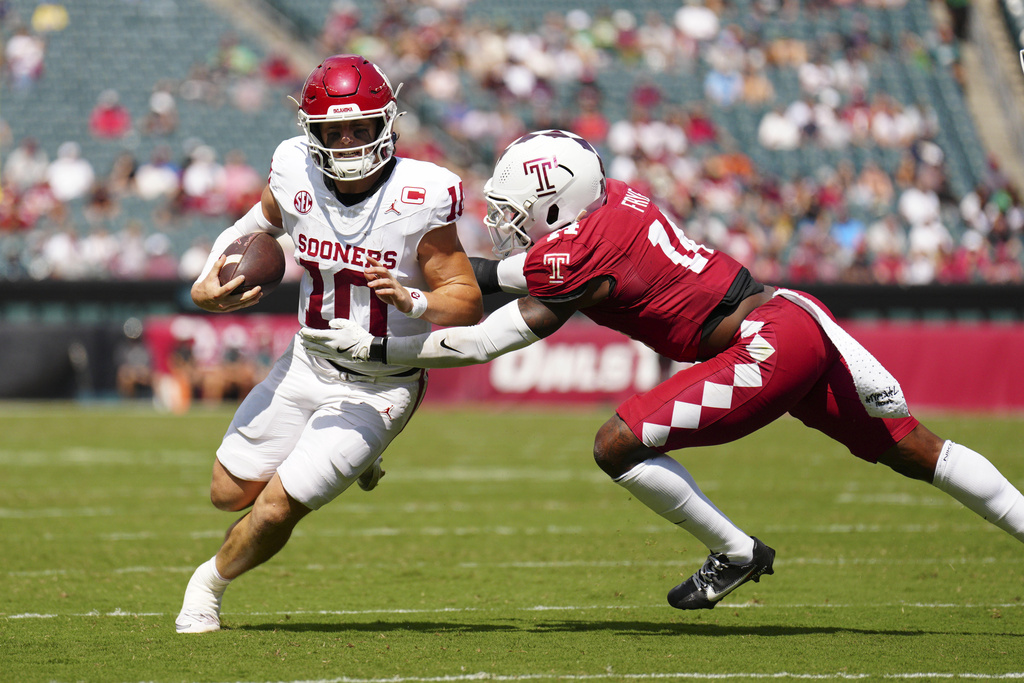 Oklahoma quarterback John Mateer, left, runs the ball against Temple safety Louis Frye (14) during the first half of an NCAA college football game, Saturday, Sept. 13, 2025, in Philadelphia. (AP Photo/Derik Hamilton)