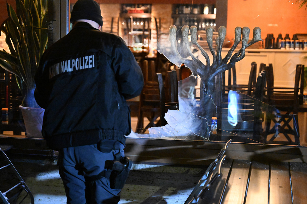 An investigator checks the damage as he stands outside an Israeli restaurant where the windows were broken early Friday, April 10, 2026, in Munich, Germany. (Felix Hörhager/dpa via AP)