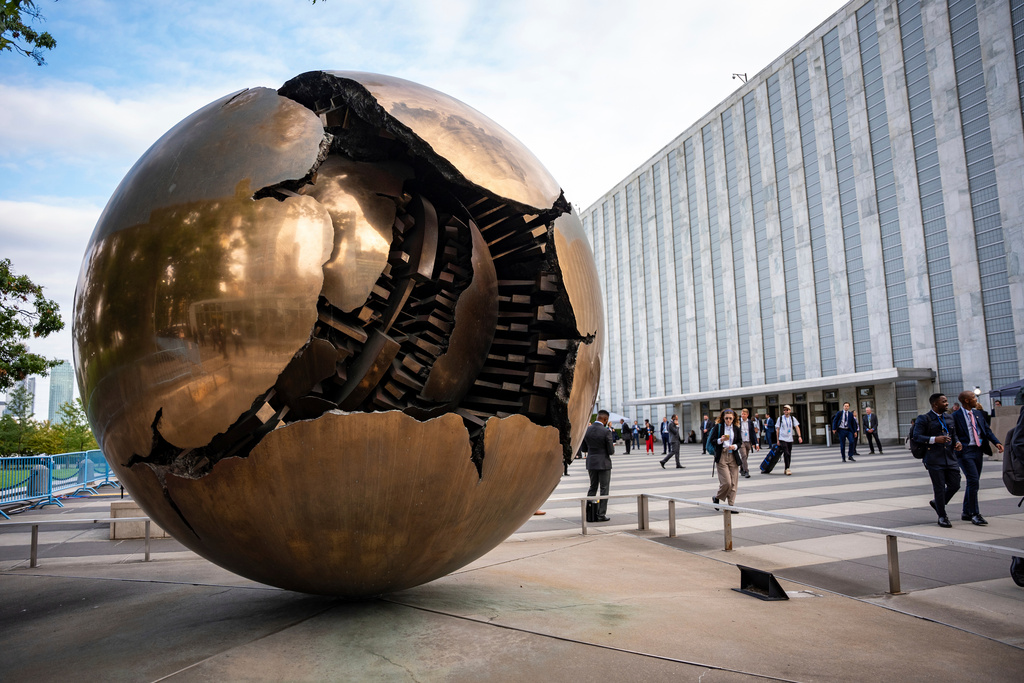FILE - People walk around the plaza by the Sphere Within Sphere outside the United Nations Headquarters on the first day of the 80th session of the UN General Assembly's High-Level week, Monday, Sept. 22, 2025. (AP Photo/Angelina Katsanis, File)