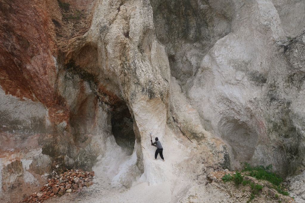 FILE - A worker pounds a wall of rock to make gravel and sand in the Kenscoff neighborhood of Port-au-Prince, Haiti, Oct. 17, 2025. (AP Photo/Odelyn Joseph)