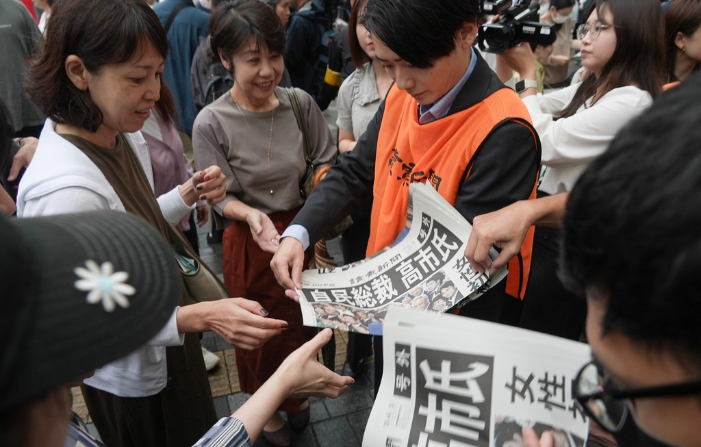 FILE - A worker distributes copies of special edition newspaper issued after Sanae Takaichi won the ruling Liberal Democratic Party leadership vote in Tokyo, Oct. 4, 2025. (AP Photo/Ayaka McGill, File)