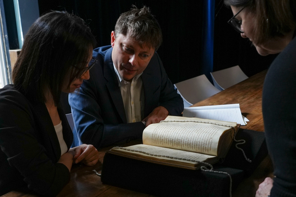 From left, Elisabetta Magnanti and Mark Faulkner from Dublin's Trinity College and Valentina Longo of Rome's National Central Library look at a manuscript containing a rare, long-lost copy of Caedmon's Hymn, the first poem ever to be written down in Old English, at Rome's National Library, Thursday, May 8, 2026. (AP Photo/Andrea Rosa)