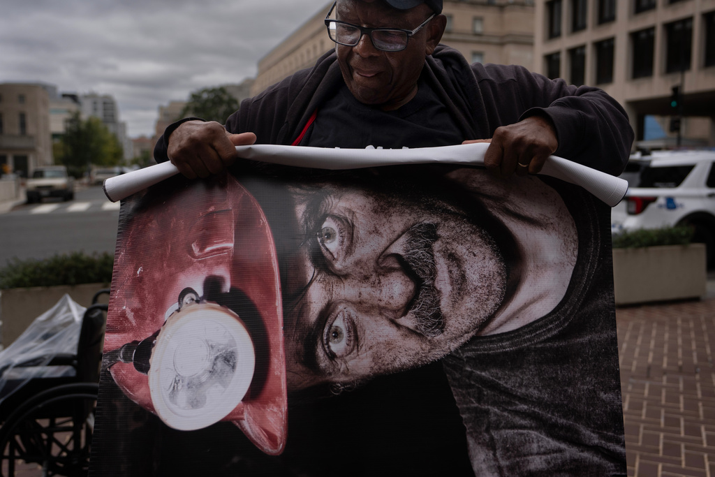Roosevelt Neal, with the Fayette County Black Lung Association in W.Va., rolls up a banner of a coal miner who died of black lung disease, during a protest outside the U.S. Department of Labor, Oct. 14, 2025, in Washington. (AP Photo/Carolyn Kaster)