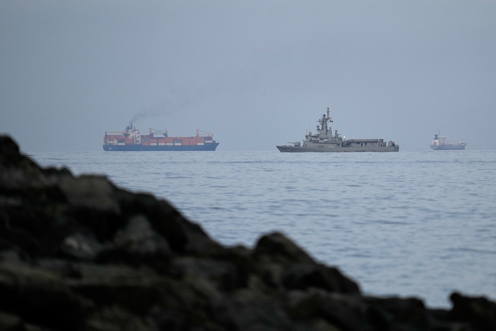 A UAE navy ship sails next to a cargo ship in the Strait of Hormuz as seen from Khor Fakkan, United Arab Emirates, Wednesday, March 11, 2026. (AP Photo/Altaf Qadri)