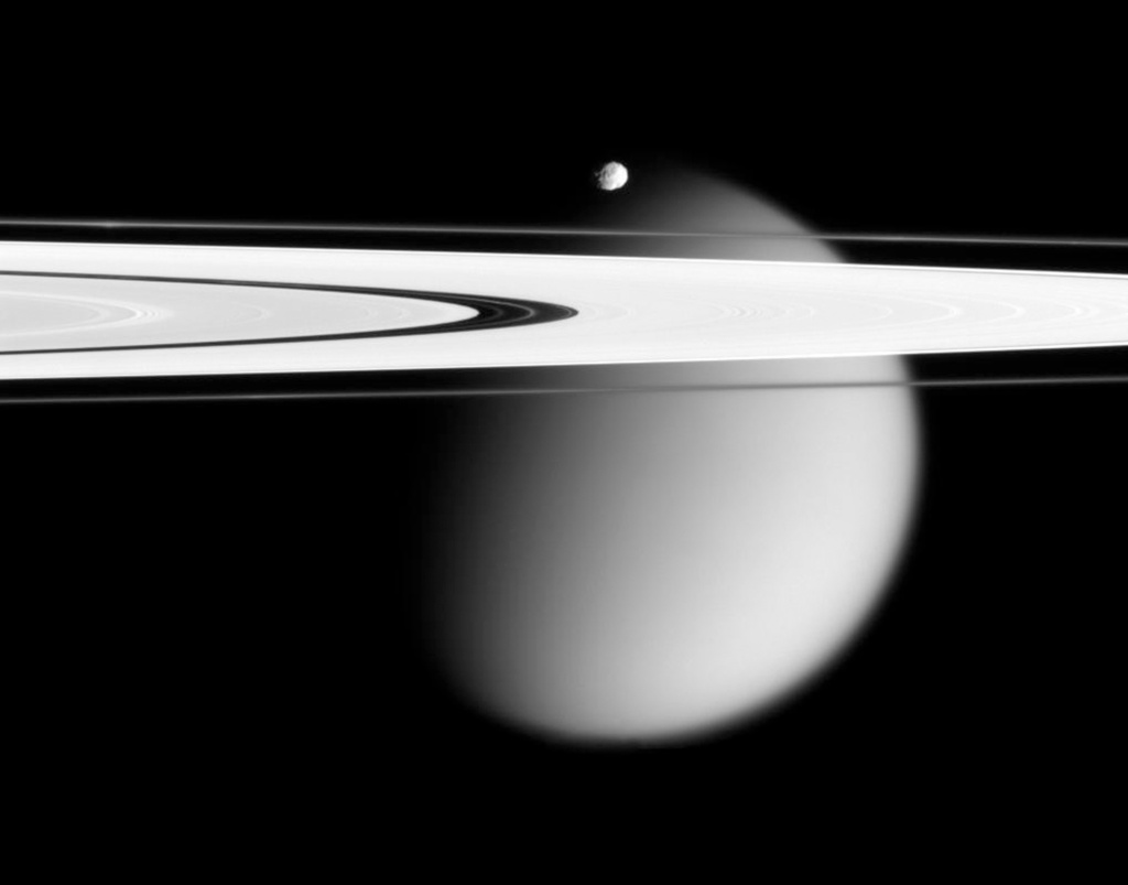 FILE - This image made by the Cassini spacecraft and provided by NASA on March 12, 2006, shows two of Saturn's moons, the small Epimetheus and smog-enshrouded Titan, with Saturn's A and F rings stretching across the frame. (NASA via AP)