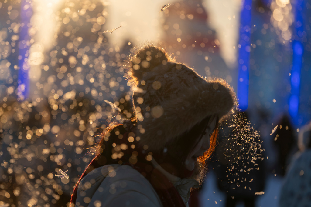 A visitor reacts to man made snow before the opening ceremony for the annual Ice and Snow Festival held in Harbin in China's Heilongjiang province on Monday, Jan. 5, 2026. (AP Photo/Ng Han Guan)
