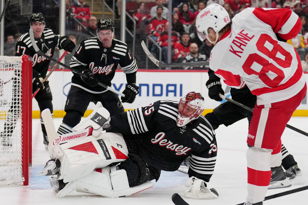 New Jersey Devils goaltender Jacob Markstrom, bottom, saves a shot made by Detroit Red Wings' Patrick Kane, right, during the third period of an NHL hockey game in Newark, N.J., Monday, Nov. 24, 2025. (AP Photo/Seth Wenig)