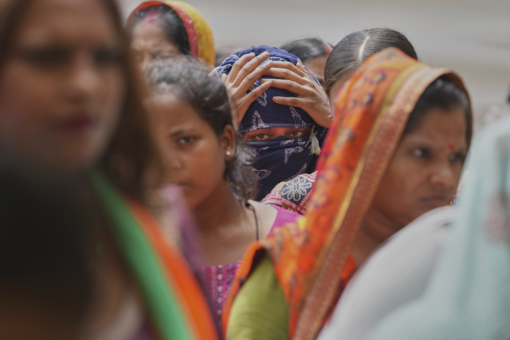 People stand in a queue for food in a temporary school shelter, which houses residents displaced from the banks of the Yamuna River by incessant rain in the higher regions in New Delhi, India, Friday, Sept. 5, 2025. (AP Photo/Manish Swarup)
