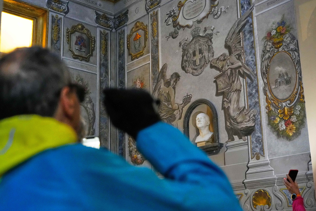 People take pictures at a restored fresco to the memory of late Italy's King Umberto II depicting Angels inside the Basilica of St. Lawrence in Lucina in Rome, Sunday, Feb. 1, 2026. (AP Photo/Gregorio Borgia)