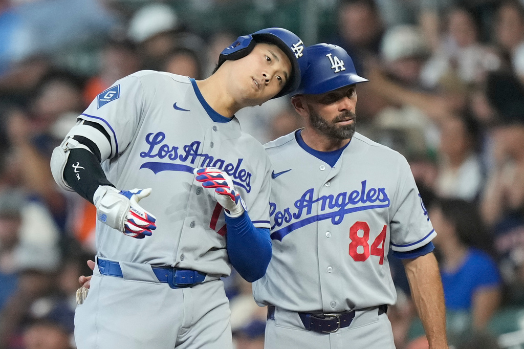 Los Angeles Dodgers designated hitter Shohei Ohtani, left, celebrates with first base coach Chris Woodward (84) after a single during the fifth inning of a baseball game against the Houston Astros in Houston, Wednesday, May 6, 2026. (AP Photo/Ashley Landis)