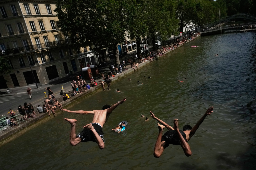 FILE - Parisians bath in the Canal Saint-Martin in Paris, as the national weather service, Meteo France, placed 54 departments, about half the country, under a red heat wave alert, on June 23, 2026. (AP Photo/Christophe Ena, File)