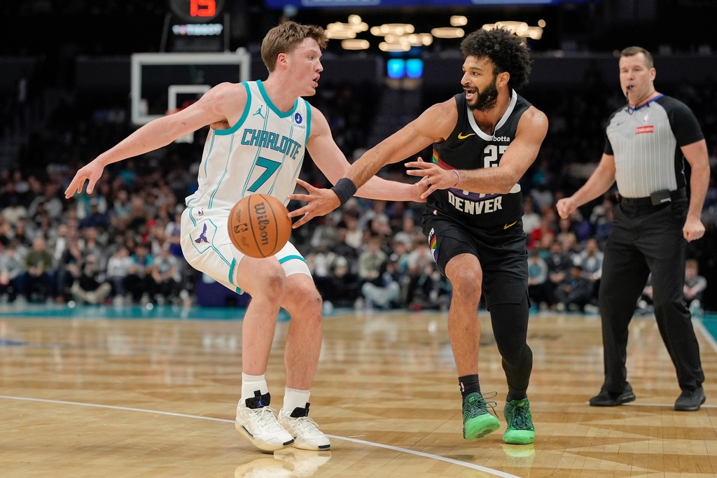 Denver Nuggets guard Jamal Murray, front right, passes the ball while defended by Charlotte Hornets guard Kon Knueppel (7) during the first half of an NBA basketball game in Charlotte, N.C., Sunday, Dec. 7, 2025. (AP Photo/Jim Dedmon)