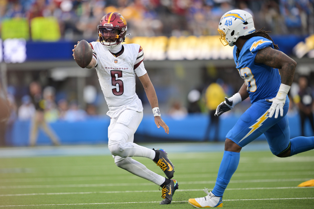 Washington Commanders quarterback Jayden Daniels (5) runs next to Los Angeles Chargers outside linebacker Bud Dupree (48) during the second half of an NFL football game Sunday, Oct. 5, 2025, in Inglewood, Calif. (AP Photo/Carrie Giordano )