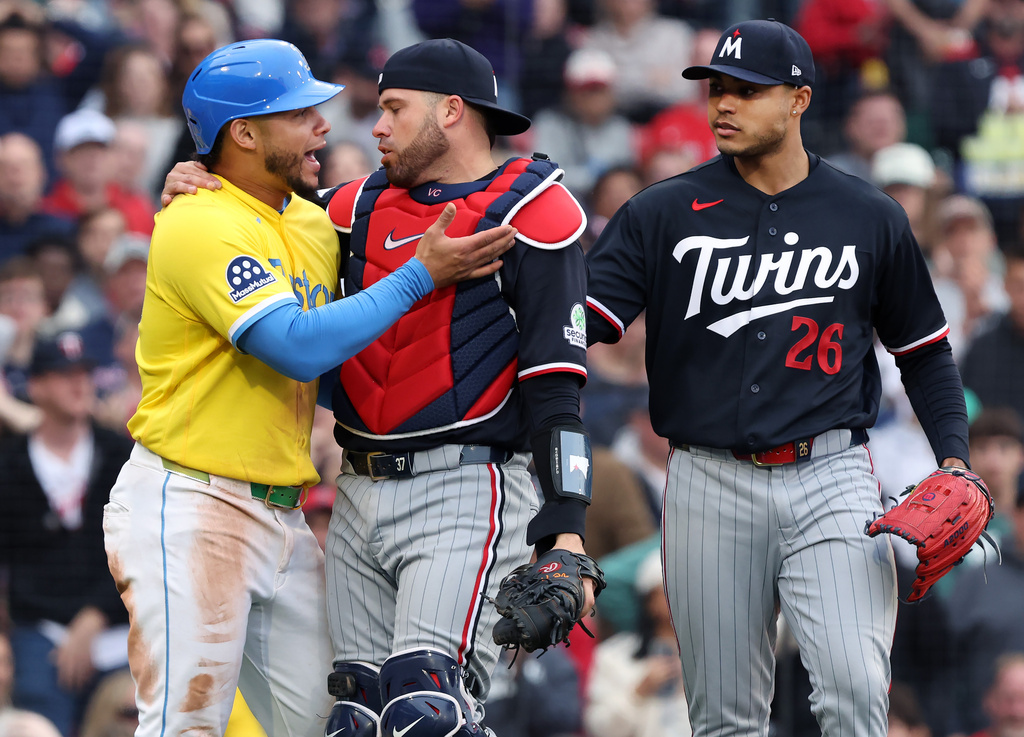 Boston Red Sox's Willson Contreras, left, and Minnesota Twins catcher Victor Caratini, center, exchange words as Twins pitcher Taj Bradley, right, looks on after a play at the plate during the fourth inning of a baseball game, Saturday, May 23, 2026, in Boston. (AP Photo/Jim Davis)