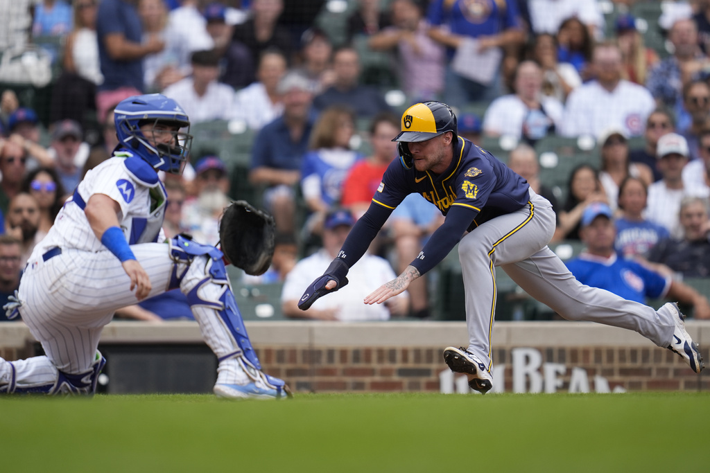 Milwaukee Brewers' Brice Turang (2) dives past Chicago Cubs catcher Reese McGuire (20) to score on a single by Sal Frelick during the sixth inning in the first baseball game of a doubleheader, Tuesday, Aug. 19, 2025, in Chicago. (AP Photo/Erin Hooley)