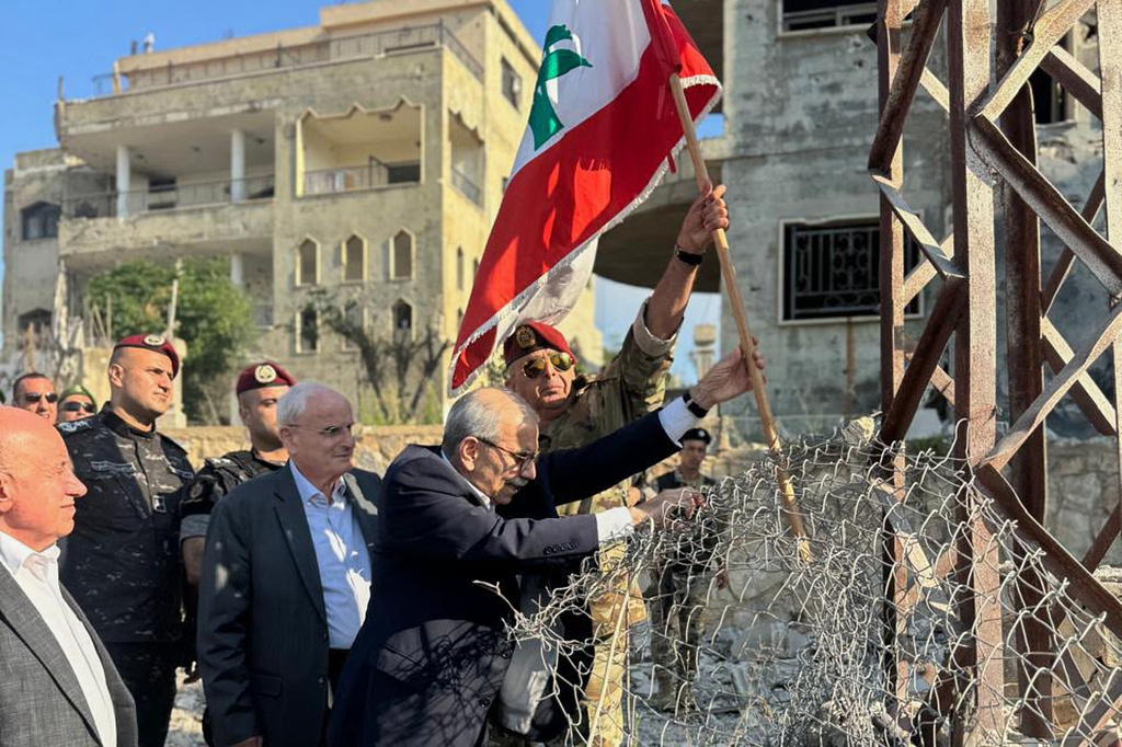 In this photo released by the Lebanese Government press office, Lebanese Prime Minister Nawaf Salam, center, raises a Lebanese flag during a visit to the southern village of Zawtar Al Gharbieh, Lebanon, Wednesday, July 22, 2026. (Lebanese Government press office via AP)
