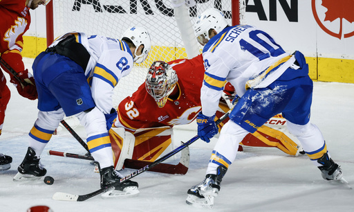 St. Louis Blues' Dylan Holloway, left, and Brayden Schenn, right, try to get the puck past Calgary Flames goalie Dustin Wolf during the third period of an NHL hockey game in Calgary, Alberta, Saturday, Oct. 11, 2025. (Jeff McIntosh/The Canadian Press via AP) St. Louis Blues' Dylan Holloway, left, and Brayden Schenn, right, try to get the puck past Calgary Flames goalie Dustin Wolf during the third period of an NHL hockey game in Calgary, Alberta, Saturday, Oct. 11, 2025. (Jeff McIntosh/The Canadian Press via AP)